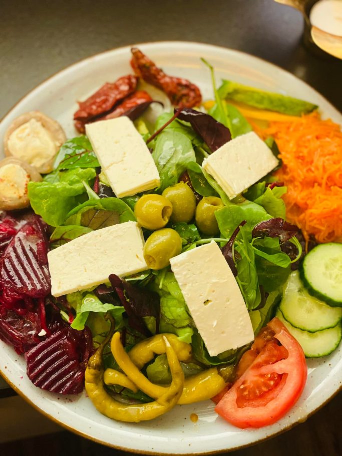 Bunt gemischter Salat mit Käse, Oliven, Gurken, Tomaten und Karottenraspel.